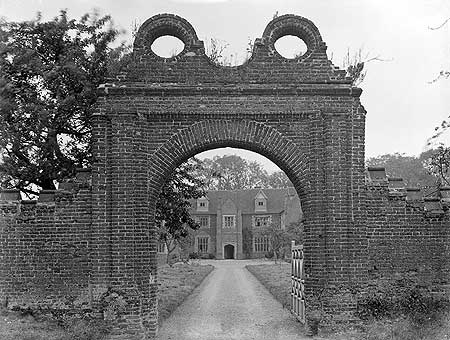 Breccles Hall, Norfolk, seen here through its entrance gateway, is an example of a brick-built 16th-century manor house. By this date building in brick was quite usual. 